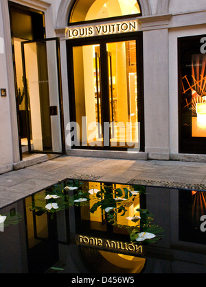 Louis Vuitton designer boutique vitrine éclairée et la réflexion dans l'eau Milan Lombardie Italie Europe Banque D'Images