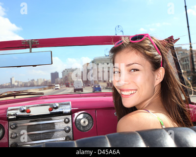 Portrait of happy young mixed race Woman / asiatique sur le siège passager en rose vintage voiture décapotable, La Havane, Cuba Banque D'Images
