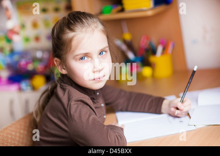 Cute little girl écrit ses devoirs à la table Banque D'Images