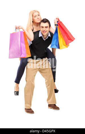 Portrait d'un jeune homme donnant un piggyback ride d'une woman with shopping bags isolé sur fond blanc Banque D'Images