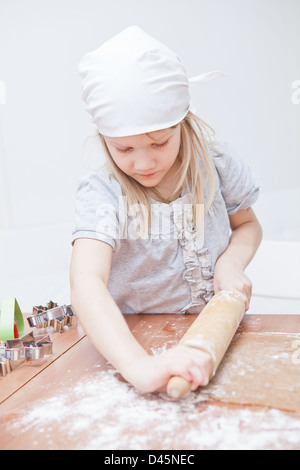 Jeune fille travaillant sur la pâte avec un rouleau à pâtisserie pour faire des biscuits de pain d'épices Banque D'Images