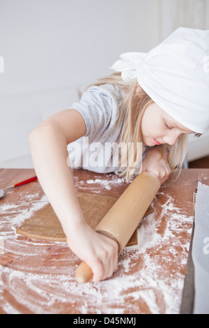 Jeune fille travaillant sur la pâte avec un rouleau à pâtisserie pour faire des biscuits de pain d'épices Banque D'Images