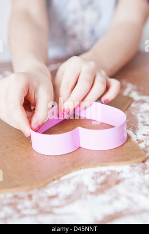 Jeune fille à partir de la coupe d'épices biscuit de pâte avec la faucheuse en forme de coeur Banque D'Images