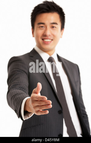 Studio Portrait of Chinese Businessman Reaching Out pour serrer la main Banque D'Images