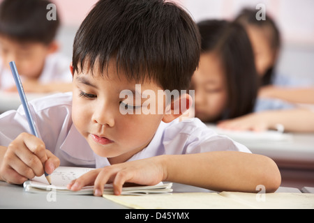 Groupe d'étudiants travaillant à un bureau en classe de l'école chinoise Banque D'Images