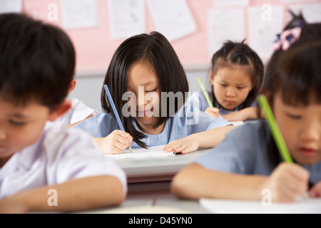 Groupe d'étudiants travaillant à un bureau en classe de l'école chinoise Banque D'Images