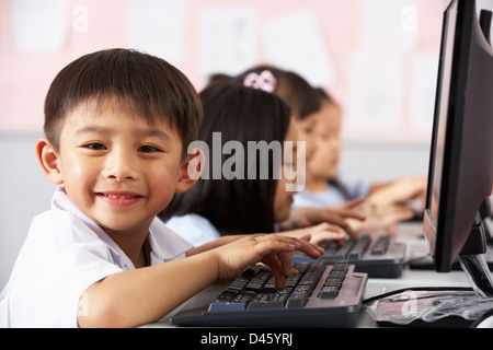 Élève de sexe masculin à l'aide clavier durant la classe d'informatique en classe de l'école chinoise Banque D'Images