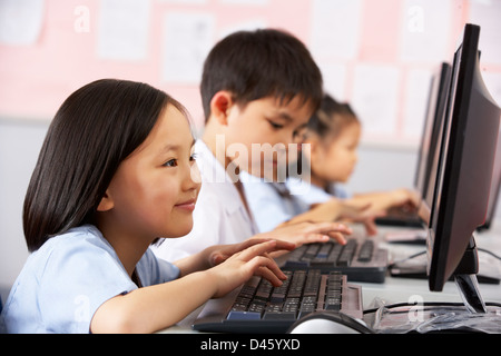 Élève de sexe féminin à l'aide clavier durant la classe d'informatique en classe de l'école chinoise Banque D'Images