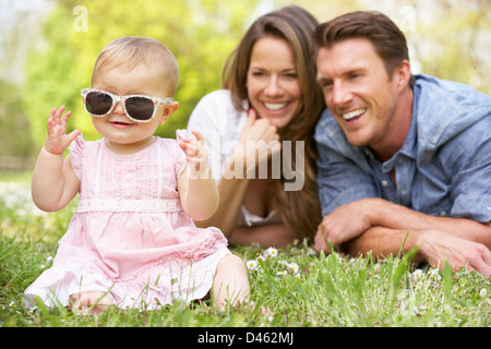 Les parents avec bébé fille assise dans le champ de fleurs d'été Banque D'Images