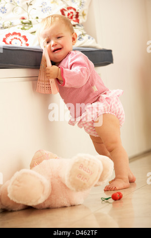 Bébé fille bouleversé d'apprendre à se lever à la maison Banque D'Images