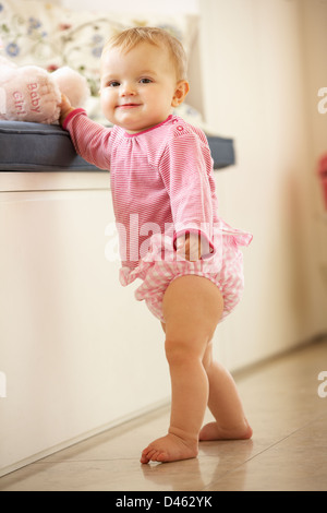 Baby Girl Learning to Stand Up à la maison Banque D'Images