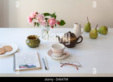 L'heure du thé et des biscuits avec un assortiment de vaisselle, vase de fleurs et studio portable sur un dessus de table Banque D'Images