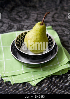 Une poire en deux plats boutonneuses sur une serviette verte à motifs noirs et tapis de table Banque D'Images