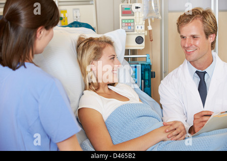 Médecin avec Nurse Talking to young female patient In Bed Banque D'Images