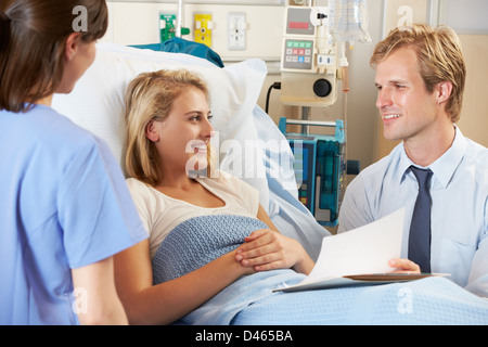 Médecin avec Nurse Talking to young female patient In Bed Banque D'Images