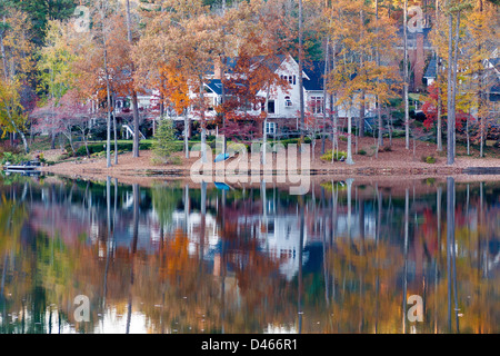 Une belle maison au bord du lac avec eau calme reflétant les arbres d'automne Banque D'Images