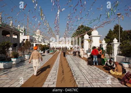 Entrée colorée pour le Temple d'or à Amritsar, Punjab avec bâtiments de marbre blanc et de guirlandes de personnes sous un ciel bleu Banque D'Images