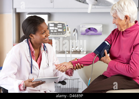 Médecin Senior femme prendre la pression artérielle du patient Banque D'Images