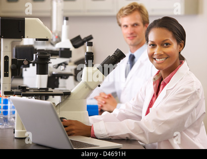 Les scientifiques masculins et féminins à l'aide de microscopes en laboratoire Banque D'Images