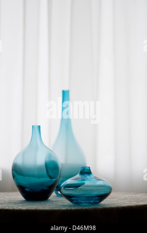 Trois vases de verre bleu s'asseoir sur une table en face d'une grande fenêtre. Banque D'Images