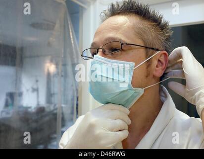 Un infirmier lui met un masque chirurgical à l'hôpital vivantes à Berlin-Spandau, Allemagne, 23 février 2013. Les germes peuvent avoir des conséquences mortelles dans les hôpitaux. Photo : Stephanie Pilick Banque D'Images