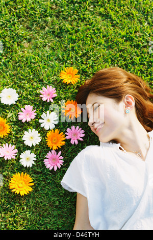 Femme avec des fleurs portant sur l'herbe Banque D'Images