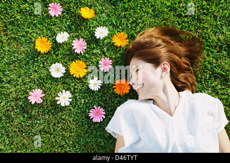 Femme avec des fleurs portant sur l'herbe Banque D'Images