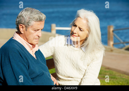 Senior Woman réconfortant déprimé mari assis sur un banc Banque D'Images