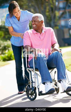 Carer poussant Senior Man In Wheelchair Banque D'Images