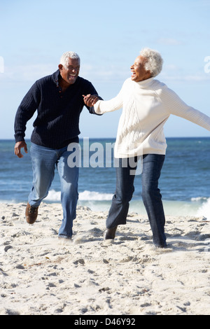 Romantic Senior Couple Running Along Beach Banque D'Images