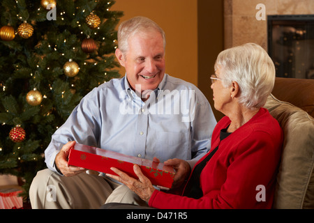 Senior Couple Exchanging Gifts in front of Christmas Tree Banque D'Images