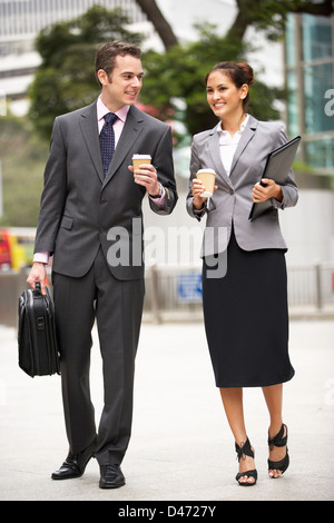 Businessman And Businesswoman Walking Along Street café à emporter Holding Banque D'Images
