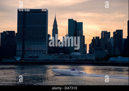 La vitesse d'un bateau le long de la rivière de l'est en face d'une silhouette d'horizon de la ville de New York, Organisation des Nations Unies et le Chrysler Building. Banque D'Images