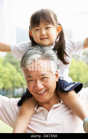 Grand-père chinois donnant petite-fille monter sur les épaules en Park Banque D'Images