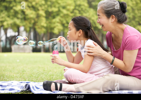 Grand-mère avec sa petite-fille chinoise dans Park Blowing Bubbles Banque D'Images