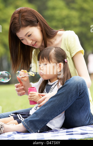 Mère Fille en chinois avec parc Blowing Bubbles Banque D'Images