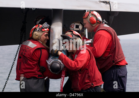 Ordnancemen Aviation affectés à l'Escadron d'avions de combat interarmées (VFA) 25 charger explosées sur un F/A-18C Hornet. Banque D'Images