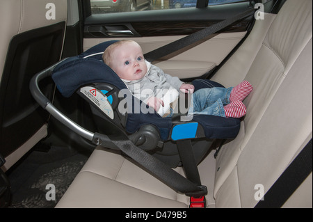 Baby Boy sixième mois assis dans un siège de voiture fixé avec une ceinture de sécurité. Banque D'Images