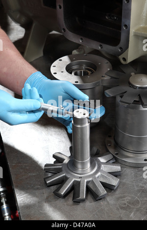 Un ingénieur utilise un micromètre pour mesurer le diamètre d'un composant du compresseur Banque D'Images