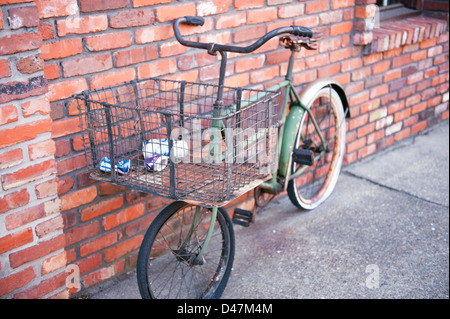 Un vintage vélo contre un mur de brique rouge avec corbeille dans panier Banque D'Images