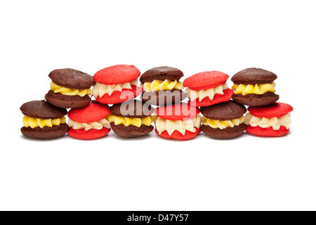 Ou coloré rouge couleur gâteaux macarons dans une rangée ou d'un groupe de deux contre un fond blanc. Banque D'Images