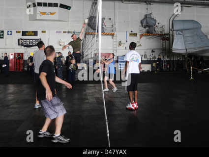 Les marins participent à un jeu de volley-ball récréatif dans la baie du hangar à bord d'un navire de la marine tout en opérant dans la mer d'Arabie, favorisant le moral pendant le déploiement. Banque D'Images