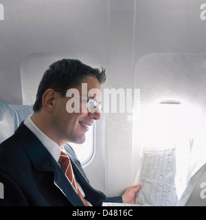 Un homme d'affaires la lecture de la partie financière d'un journal tout en voyageant dans un avion. Banque D'Images