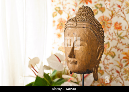 Tête de Bouddha en face de papier peint fleuri Banque D'Images
