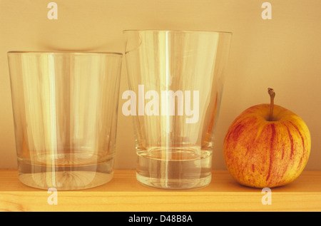 Vue de la hauteur des yeux de l'étroitesse de la planche en bois avec deux verres vides et Apple rouge et jaune Banque D'Images