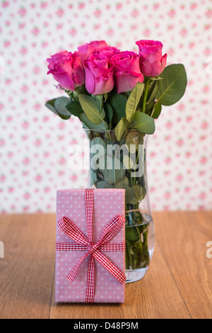 Bouquet de roses roses dans un vase avec une rose appuyé contre elle Banque D'Images