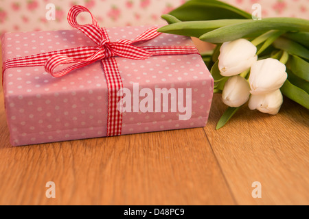 Pink wrapped present avec bouquet de tulipes blanches Banque D'Images
