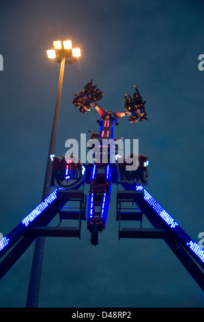 Les gens à l'envers sur un spectaculaire parc d'ride dans la soirée avec un ciel bleu en arrière-plan. Banque D'Images