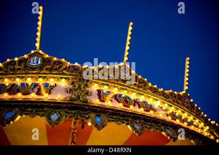 Une vue de la partie supérieure d'une traditionnelle vintage fairground ride galloper, bien éclairée avec un sombre ciel bleu en arrière-plan Banque D'Images