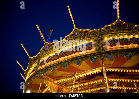 Une vue de la partie supérieure d'une traditionnelle vintage fairground ride galloper, bien éclairée avec un sombre ciel bleu en arrière-plan Banque D'Images